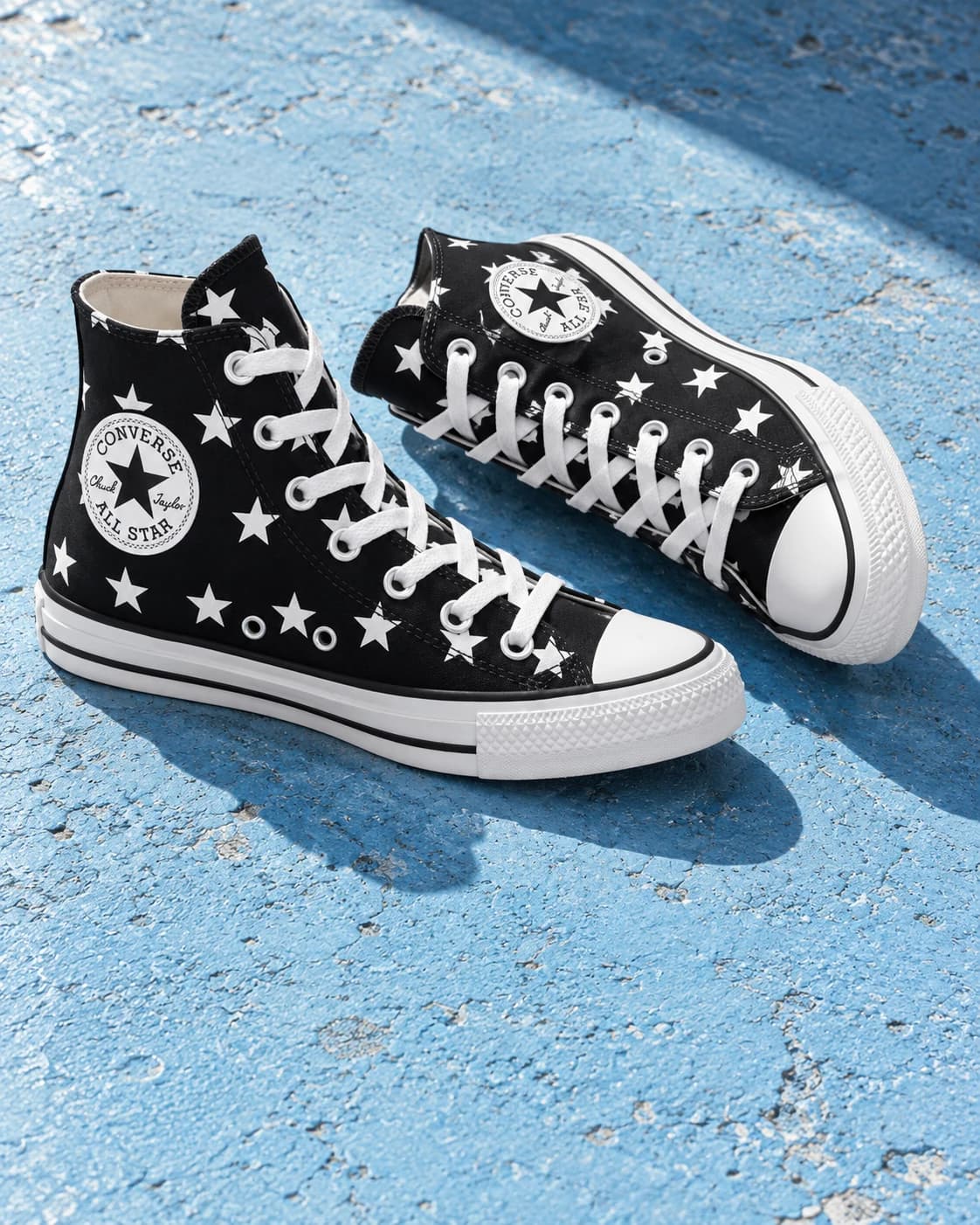 Converse Chuck Taylor All Star negras con estrellas sobre fondo azul